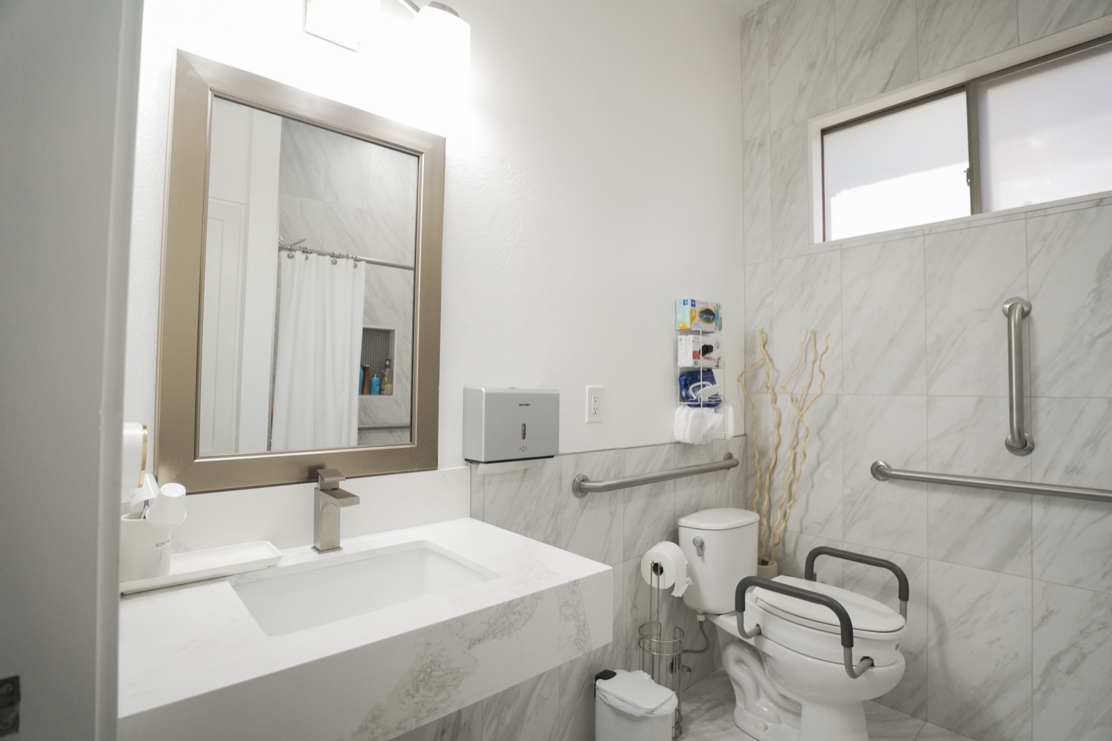 An accessible bathroom with a marble walk-in area, grab bars, and easy access for elderly residents