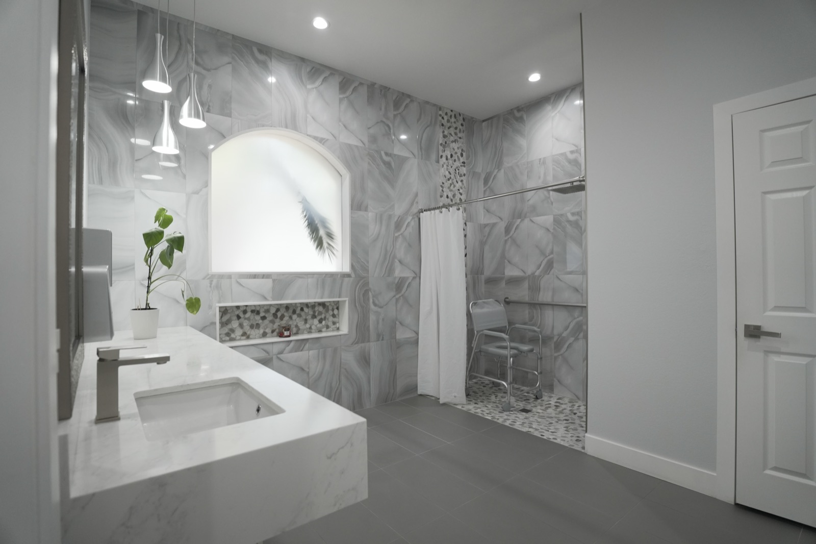 A clean marble accessible bathroom with a walk-in shower