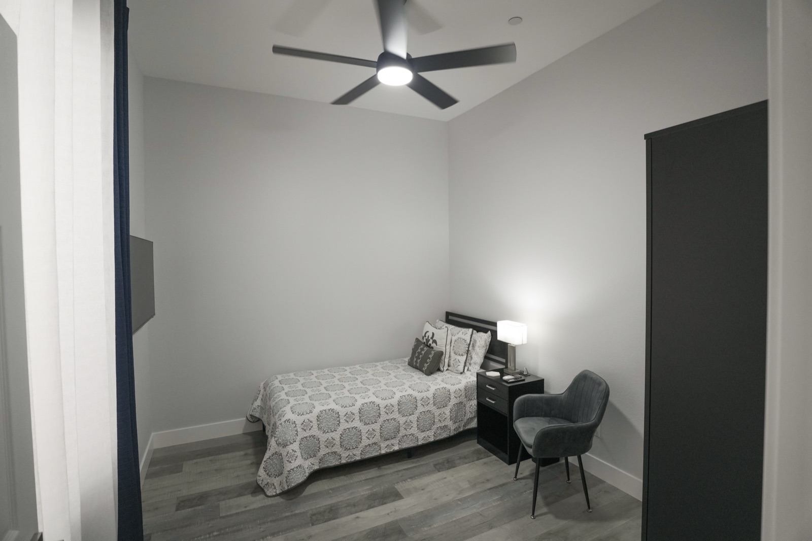 A cozy private bedroom with a patterned bedspread and an accent chair
