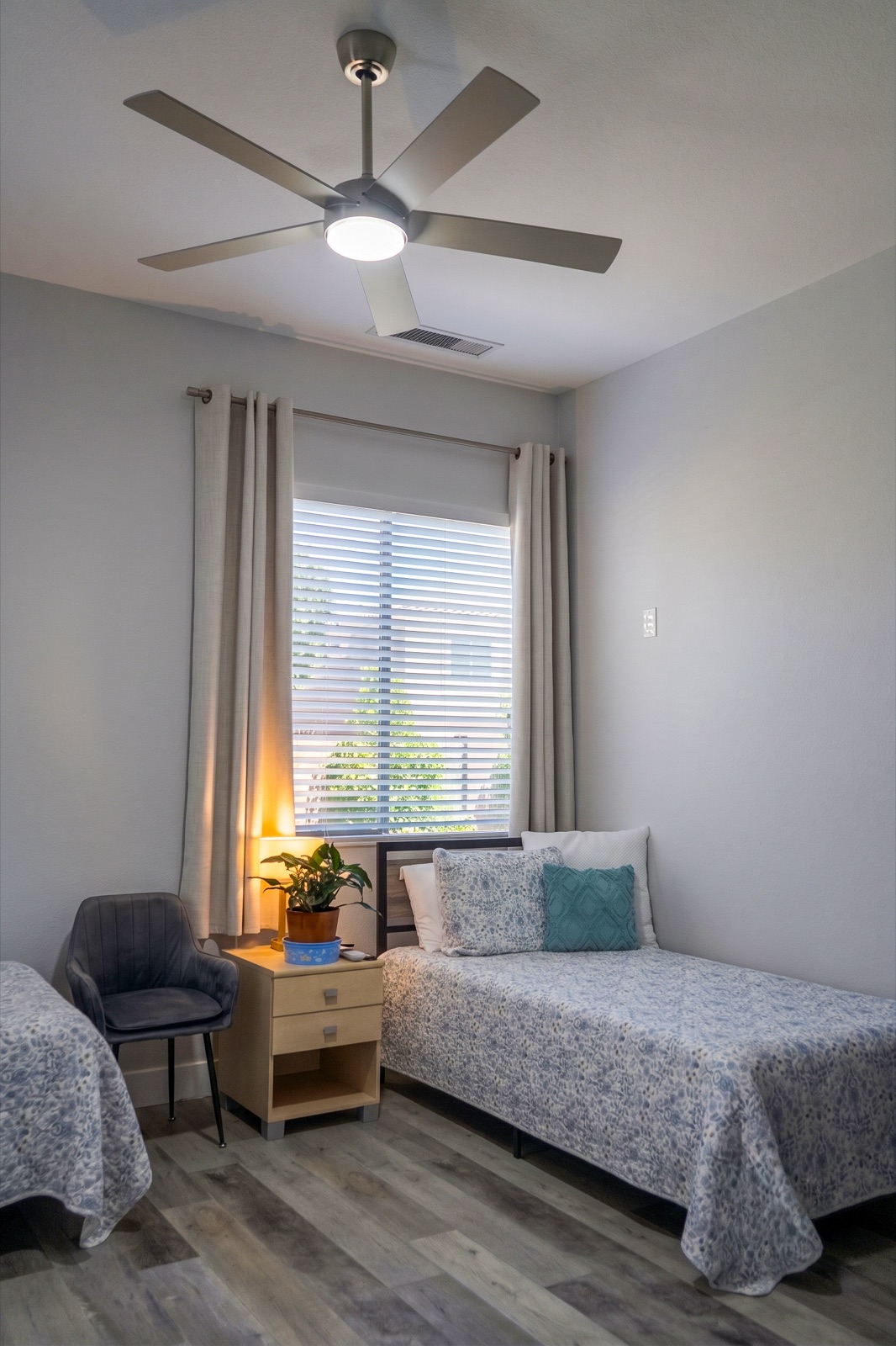 A private bedroom with soft teal accents and a large window